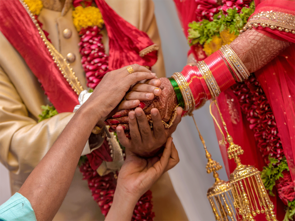 Hands of the bride in the hands of the groom performing marriage ritual.